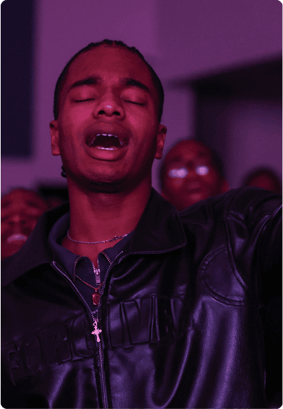 Picture of a man on his knees on the floor praying in a crowd of people